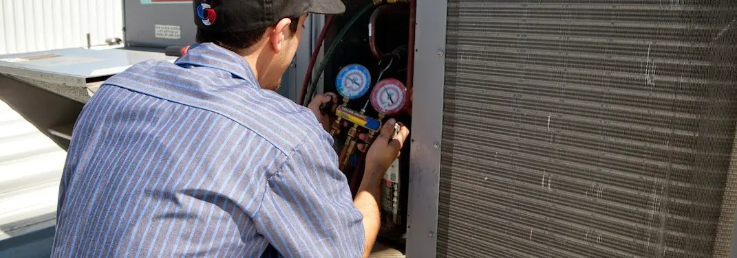 HVAC technician servicing a condenser unit in Barnstable Town